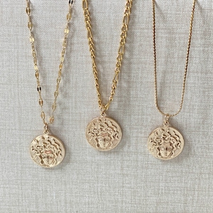 Peut inclure: Trois colliers en or avec un pendentif t&ecirc;te de M&eacute;duse. Chaque collier a un style de cha&icirc;ne diff&eacute;rent.