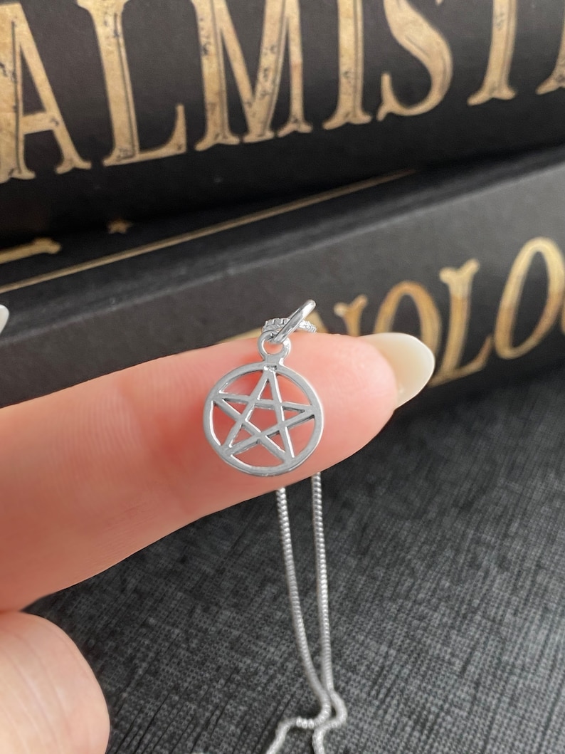May include: A silver chain necklace with a small, silver pentacle pendant.