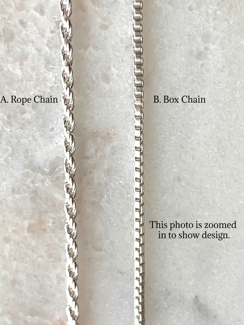 May include: Close-up of two silver chains, a rope chain and a box chain. The photo is zoomed in to show the design.