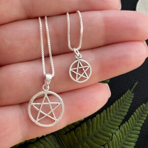 May include: Two silver necklaces with pentacle pendants. The necklaces are on a chain and the pendants are different sizes.