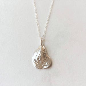 May include: A silver necklace with a delicate chain and a pendant shaped like an oyster shell.