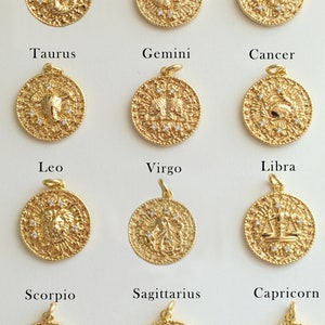May include: Twelve gold zodiac pendants with white gemstones. Each pendant features a different zodiac sign, including Aquarius, Pisces, Aries, Taurus, Gemini, Cancer, Leo, Virgo, Libra, Scorpio, Sagittarius, and Capricorn.