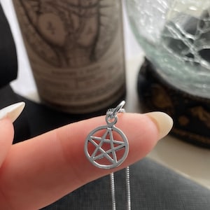 May include: A silver chain necklace with a silver pendant featuring a pentagram design.