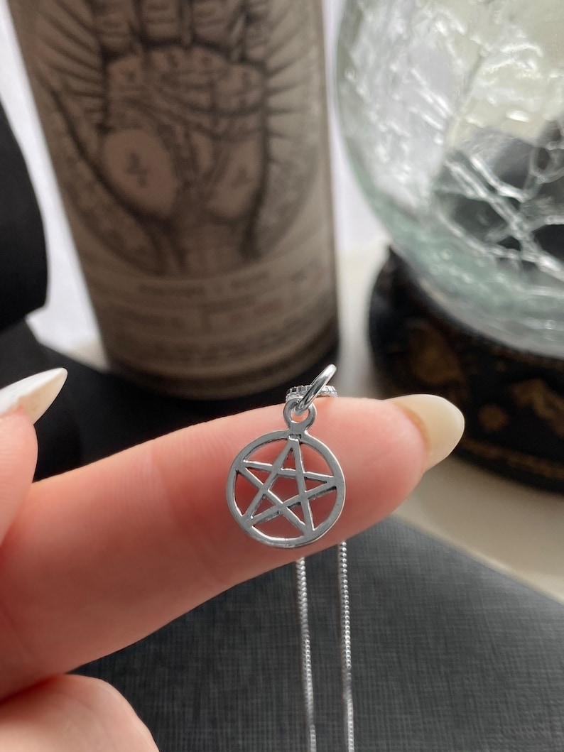 May include: A silver chain necklace with a silver pendant featuring a pentagram design.