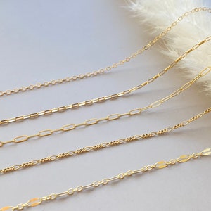 May include: Four gold chains of different lengths and styles, including a delicate chain, a curb chain, a box chain, and a cable chain. The chains are arranged on a white background.