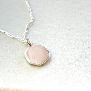 May include: A silver chain necklace with a silver octagonal pendant.