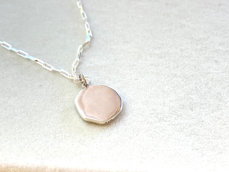 May include: A silver chain necklace with a silver octagonal pendant.