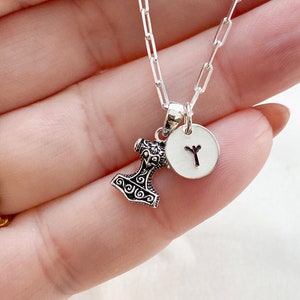 May include: A silver chain necklace with a silver Mjolnir hammer charm and a silver disc charm with a Y rune engraved on it.