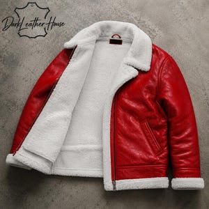 May include: A bright red jacket with a white faux shearling lining, a wide fold-over collar, and a front zipper closure. The jacket features long sleeves with white cuffs and a logo in the upper left corner that reads Dark Leather House.