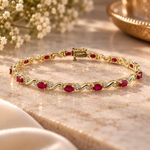 May include: A gold link bracelet featuring alternating oval-cut red rubies and small round clear stones. The bracelet has a polished yellow gold finish and a secure box clasp mechanism, showcasing a repeating pattern of gemstones set in metal links.