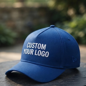 以下が含まれることがあります： フロントパネルに白い刺繍で「CUSTOM YOUR LOGO」と書かれたロイヤルブルーの野球帽。この帽子は構造化されたクラウン、カーブしたつば、サイドパネルに小さな刺繍ロゴを備えており、クラシックなアスレチックデザインが特徴です。