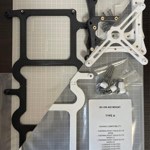 May include: A BC-250 AIO MOUNT TYPE A kit including black and white plastic mounting brackets, metal screws, and springs in clear plastic bags. A printed instruction card lists compatibility with Thermalright and Corsair cooling systems.