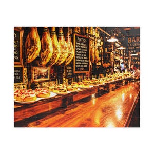 May include: A jigsaw puzzle depicting a Spanish bar interior with cured ham legs hanging from the ceiling, a wooden counter filled with various pintxos appetizers, and a chalkboard menu listing items like Jamón Ibérico and Queso Manchego.