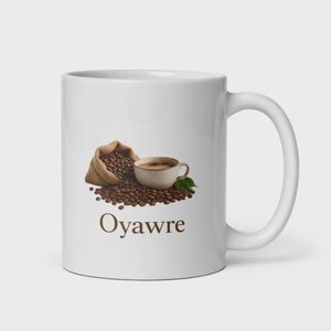Könnte beinhalten: Ein weißer Keramikbecher mit einer Grafik, die einen Jutesack zeigt, aus dem geröstete Kaffeebohnen neben einer kleinen Kaffeetasse mit einem grünen Blatt herausfallen. Der Text Oyawre ist in braunen Buchstaben unter der Grafik aufgedruckt.