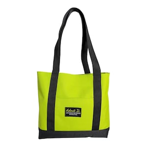 May include: A lime green tote bag with black straps and a black base. A rectangular black patch is centered on the front, featuring the yellow text "Admit It." followed by the smaller white text "LIFE WOULD BE BORING WITHOUT ME."