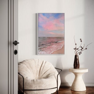 May include: A framed painting depicting a pink and blue sunset over a beach with waves breaking on the shore.