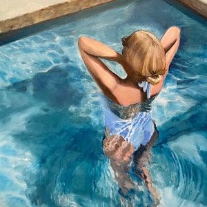 May include: A woman with blonde hair is submerged in a swimming pool. She is wearing a light blue swimsuit and has her arms raised above her head. The water is a vibrant blue and there are ripples on the surface.