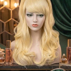 May include: A light blonde wig with a voluminous bouffant style, side-swept bangs, and loose, wavy lengths. The wig is displayed on a mannequin head, featuring a smooth, layered texture and a bright, uniform platinum-toned blonde color throughout.