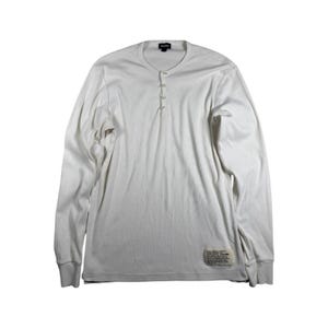 May include: A long-sleeve white henley shirt featuring a four-button placket at the neckline, a round collar, and a small rectangular fabric label with printed text near the bottom hem. The garment is made of a solid white knit fabric.
