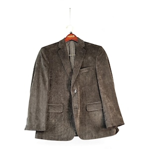 May include: A brown corduroy blazer featuring a notched lapel, two front buttons, and two flap pockets at the waist. The jacket includes a single chest pocket and is displayed on a wooden hanger with the Macy's logo printed on the front.