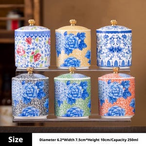Puede incluir: Seis botes cilíndricos de cerámica con tapa, cada uno con un pomo dorado. Los botes presentan varios diseños florales en azul, amarillo, verde, naranja y multicolor. Cada unidad mide 6,2 cm de diámetro y 10 cm de altura.