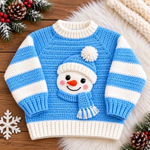 May include: A light blue and white crocheted jumper featuring a central snowman appliqué. The snowman wears a blue hat with a white pom-pom and a matching blue scarf. The jumper has long sleeves with horizontal blue and white stripes.