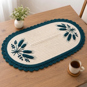 May include: An oval-shaped crochet table runner featuring a cream-colored center with a textured stitch pattern and a dark teal scalloped border. The runner is decorated with two embroidered dark teal wheat-like botanical motifs on each end.