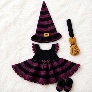 Può includere: Un set all'uncinetto composto da un cappello a punta a righe nere e viola con una fibbia gialla, un vestito a righe nere e viola con maniche a volant e un fiocco centrale, una piccola scopa con setole gialle e due scarpe nere con fiocchi viola.