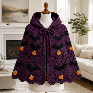 May include: A deep purple crochet hooded cape featuring a repeating pattern of black bats and orange pumpkins. The garment includes a scalloped hem, a front tie closure, and intricate spider web motifs integrated into the textured yarn design.