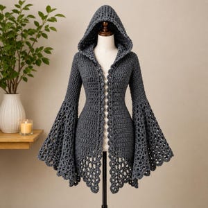 May include: A dark gray crochet hooded cardigan featuring long, wide bell sleeves with an intricate openwork pattern. The garment has a fitted bodice, a front button closure, and a scalloped hemline that extends into a delicate lace-like design.