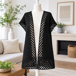 May include: A black sleeveless crochet cardigan featuring a classic granny square pattern along the front edges and bottom hem, with a solid stitch design on the main body panels, displayed on a white mannequin torso.