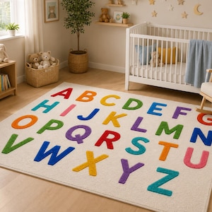May include: A rectangular area rug featuring the English alphabet in large, colorful, raised letters. The letters are arranged in rows against a cream-colored background, displaying a variety of colors including red, orange, yellow, green, blue, and purple.