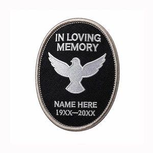 May include: An oval-shaped black embroidered patch with a silver border. It features a white dove graphic in the centre with the text IN LOVING MEMORY above it, and the placeholder text NAME HERE and 19XX-20XX printed in white below the dove.