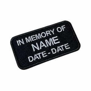 May include: A rectangular black embroidered patch with rounded corners featuring white stitched text that reads IN MEMORY OF, followed by NAME, and finally DATE-DATE. The patch has a thick black border and a clean, uniform fabric texture.