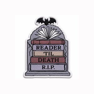 Peut inclure: Un écusson brodé en forme de pierre tombale avec une chauve-souris noire au sommet. Il représente une pile de livres surmontée d'un livre ouvert. Les tranches portent le texte READER, TIL, DEATH et R.I.P. en lettres noires sur fond coloré.