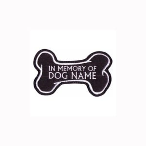 May include: A black embroidered patch shaped like a dog bone with a white border. The text IN MEMORY OF DOG NAME is stitched in white thread across the center of the patch. The design features a clean, bold font and a distinct bone silhouette.
