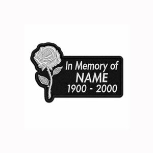 Puede incluir: Un parche bordado negro de forma rectangular con una rosa blanca a la izquierda y el texto blanco In Memory of NAME 1900 - 2000 a la derecha. El parche tiene un borde negro y una rosa blanca con pétalos y hojas detallados.