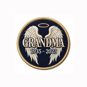 May include: A circular embroidered patch with a dark blue background and a gold stitched border. The design features white angel wings, a gold halo, and the white text GRANDMA followed by the years 1935 - 2023 in a white serif font.