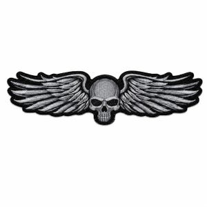 May include: An embroidered patch featuring a central human skull in shades of gray and white, flanked by two large, detailed feathered wings extending horizontally. The entire design is outlined with a thick black border on a white background.