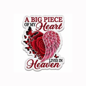 May include: An embroidered patch featuring a red rose heart with a pink angel wing on the right side and black butterflies on the left. The text reads A BIG PIECE OF MY Heart LIVES IN Heaven in red and black lettering on a white background.