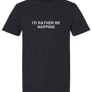 May include: A black short-sleeved t-shirt featuring the white text I'D RATHER BE NAPPING printed in a clean, sans-serif font across the center of the chest. The garment has a classic crew neckline and a straight hemline, providing a simple design.