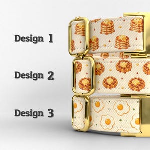 Puede incluir: Tres collares para mascotas apilados con herrajes de metal en tono dorado. El dise&ntilde;o 1 presenta un patr&oacute;n de panqueques, el dise&ntilde;o 2 muestra un estampado de gofres y el dise&ntilde;o 3 exhibe un motivo de huevos fritos sobre un fondo color crema.