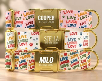 May include: Three pet collars with gold-tone metal buckles engraved with names Cooper, Stella, and Milo and the phone number 123-456-7890. The collars feature a colorful pattern of the words Live, Laugh, Love, paw prints, and bone icons.