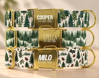 May include: Three pet collars featuring a forest pattern with green pine trees, mountains, and brown pinecones on a cream background. Each collar has a gold-tone metal side-release buckle engraved with a name and phone number: COOPER, STELLA, or MILO.