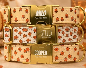 May include: Three pet collars stacked vertically, each featuring a gold-tone metal buckle engraved with a name and phone number. The top collar says MILO, the middle says STELLA, and the bottom says COOPER. All feature orange pumpkin patterns.