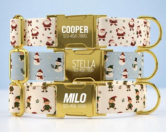 May include: Three pet collars with gold-tone metal buckles. The top collar is cream with Santa Claus figures, labeled COOPER 123-456-7890. The middle is light blue with snowmen, labeled STELLA 123-456-7890. The bottom is cream with elves, labeled MILO 123-456-7890.