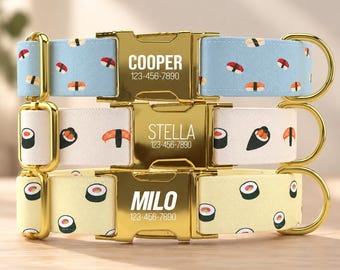 May include: Three pet collars with gold-tone metal buckles and hardware. The top collar is light blue with sushi patterns, the middle is white with sushi, and the bottom is pale yellow with sushi. Each buckle is engraved with a name and phone number.