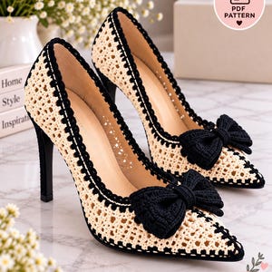 May include: A pair of pointed-toe high heels featuring a cream-colored crocheted mesh upper with black trim and a prominent black crocheted bow on the toe. The heels have a black stiletto heel and a beige interior lining. Includes a PDF PATTERN label.