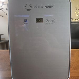 Puede incluir: Una incubadora de laboratorio IVYX Scientific plateada con acabado de metal cepillado. El panel frontal cuenta con una pantalla digital de temperatura, un botón de encendido azul iluminado y controles táctiles de más y menos para ajustar.