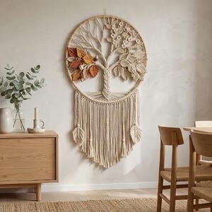 May include: A circular macrame wall hanging featuring a tree design with braided trunk and branches. One side displays textured orange and brown fabric leaves, while the other side features cream-colored macrame flowers and foliage with long fringe.
